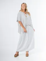 Blusa tipo poncho confeccionada en lino italiano color gris claro, con escote en V y calce amplio.