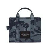 Bolso tote de Marc Jacobs en tejido jacquard con estampado de camuflaje en tonos verdes y negros. Presenta el logo de la marca bordado en relieve en el frente, doble asa superior y correa de hombro ajustable y extraíble.