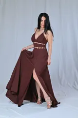 Vestido largo color beige, con breteles finos y escote en V. Presenta detalles de argollas doradas en la cintura y en el busto.