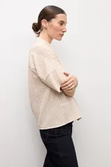 Camisa de manga corta con diseño a rayas en tonos beige y blanco, cuello camisero y cierre frontal con botones ocultos.
