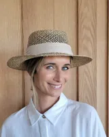 Sombrero de paja con ala ancha y cinta de tela color crema.