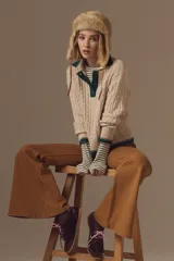 Sweater de punto con diseño de ochos, color crudo, con cuello polo y detalles en color verde en el cuello, puños y ruedo.