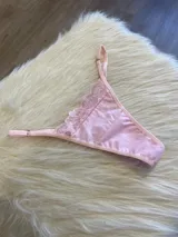 Tanga rosada de algodón con encaje en la parte delantera y tiras regulables.