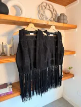 Chaleco negro de crochet sin mangas, con escote en V pronunciado y terminación de largos flecos colgantes en el ruedo.