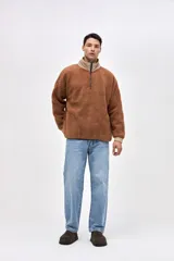 Buzo de sherpa con textura capitoneada, diseño de medio cierre y cuello alto en color beige contrastante. Presenta un calce holgado, mangas largas con puños elásticos y bolsillos laterales.