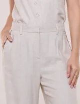 Pantalón wide leg de lino color beige, con silueta amplia, pretina con pasacintos, bolsillos laterales con detalles bordados a contraste y ruedo ancho.