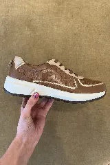 Championes de cuero en tonos marrón y tostado, con diseño combinado que incluye paneles con textura símil cocodrilo y detalles metalizados en dorado, suela blanca y cordones marrones.