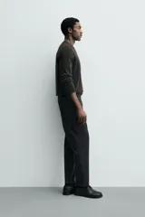 Pantalón de corte regular fit, color negro, confeccionado en tejido elástico. Presenta cintura elástica, cierre frontal con cremallera y botón, bolsillos laterales y bolsillos traseros de vivo.
