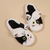Pantuflas de diseño sin talón con forma de gato, confeccionadas en piel sintética suave. Presentan un patrón bicolor en blanco y negro con detalles bordados de ojos, nariz y bigotes, y cuentan con suela de goma antideslizante.