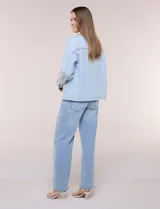 Campera de denim blanco de corte holgado con hombros caídos, cuello con solapa en contraste de color celeste, cierre frontal con botones metálicos y bolsillos delanteros con solapa.