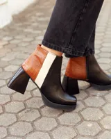 Botinetas de cuero con diseño tricolor en negro, marrón con textura croco y blanco. Presentan taco cuadrado, plataforma y cierre lateral.