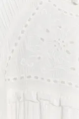 Camisa blanca de manga larga con cuello redondo y diseño abullonado, con detalle de bordados y encaje en la parte frontal y cierre de botón en la espalda.