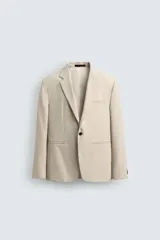 Blazer de corte regular fit confeccionado en tejido con lana. Presenta cuello con solapas de muesca, cierre frontal de un botón, bolsillos de vivo en el pecho y en la cadera, y aberturas en la espalda.