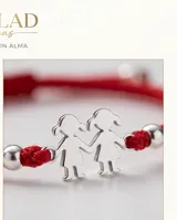 Pulsera de hilo rojo tejida en macramé con dijes centrales de dos figuras de nenas en plata 925 y terminaciones con esferas de plata.