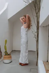 Vestido largo blanco de corte recto, con tirantes finos, escote recto y costuras pespunteadas visibles que estructuran la silueta.