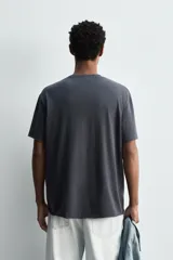 Camiseta relaxed fit de algodón ligero, color gris oscuro, con cuello redondo y manga corta con acabados irregulares. Pertenece a la colección especial Origins.