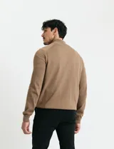 Cardigan de punto color marrón, con cuello alto y cierre frontal completo. Presenta mangas largas tipo ranglan y bolsillos laterales de ribete.
