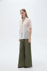 Blusa blanca de lyocell con cuello solapa, mangas cortas y cierre frontal mediante cordones para anudar.