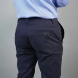 Pantalón de gabardina color azul marino, de corte ajustado y tiro medio, con cierre y botón frontal.
