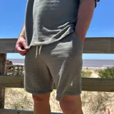 Short de tejido texturizado color beige, con cintura elastizada y cordón ajustable.