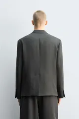 Blazer de corte relajado confeccionada en lana de origen italiano, con diseño de doble botonadura cruzada. Presenta cuello con solapas de muesca, manga larga con botones en puños, bolsillos con solapa en la cadera y abertura central en la espalda. Incluye forro interior a contraste.