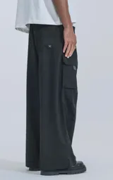 Pantalón técnico negro de silueta oversize, con cintura elástica, bolsillos cargo laterales y un cinturón de cinta con hebilla de plástico.