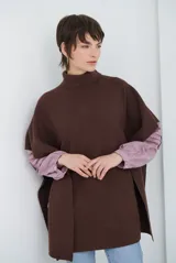 Poncho de tejido de punto acanalado en color marrón, con cuello alto y diseño holgado sin mangas.