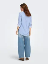 Camisa de corte suelto y textura fluida, con estampado de rayas verticales en azul y blanco. Presenta cuello camisero, cierre frontal de botones y mangas largas con opción de enrollado.