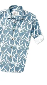 Camisa celeste con estampado de hojas blancas, de manga larga con puños enrollados y cuello clásico.