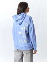 Canguro lila con capucha y cordones ajustables. Estampado frontal con la palabra "Whatever" en letras plateadas.