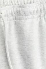 Pantalón de jogging de felpa color gris melange, con interior cepillado suave. Presenta cintura elástica fruncida con cordón ajustable, bolsillos laterales y elástico revestido en los bajos.