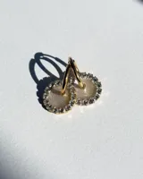 Aros de acero quirúrgico con dije circular de resina rosa y borde de strass dorados.