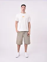 Remera de manga corta color beige claro, con cuello redondo y un pequeño estampado de un sol amarillo con texto en el pecho.