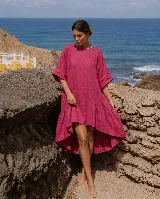 Vestido corto de lino color blanco, con mangas cortas amplias, escote redondo y diseño asimétrico más corto en la parte delantera y con volados en el ruedo.