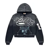 Campera con capucha y cierre frontal, de corte boxy fit. Presenta un diseño desgastado con costuras visibles en contraste, estampado gráfico frontal con texto y detalles bordados en las mangas.