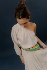 Blusa blanca de un solo hombro con manga larga abullonada y diseño holgado.