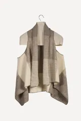 Chaleco sin mangas de lana fina sin teñir, color crudo, con cuello volcado y diseño a cuadros sutil. Presenta terminación a mano en crochet.