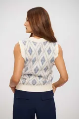 Chaleco de tejido de punto color crema con diseño de rombos en azul claro, escote en V y sin mangas.