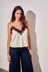 Blusa satinada marrón con detalles de encaje en el escote en V y en el ruedo. Presenta tirantes finos regulables.