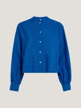 Camisa azul con cuello mao, corte cropped, mangas largas abullonadas con puño y cierre frontal con botones. Confeccionada en mezcla de modal ligera con acabado texturizado.