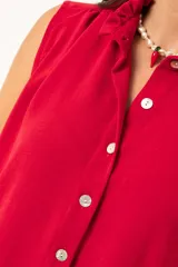 Camisa roja sin mangas con cuello mao adornado con un volado y cierre frontal con botones.