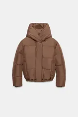 Campera puffer acolchada de color negro, con cuello envolvente, capucha integrada, manga larga, bolsillos laterales ocultos y bajo con elástico. Cierre frontal con botones a presión ocultos por solapa.