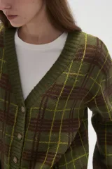 Cardigan de punto con diseño de cuadros, cuello en V y cierre frontal con botones. Presenta un corte holgado y mangas largas.