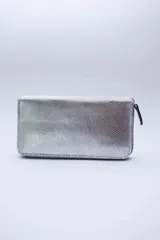 Billetera plateada con textura símil piel de reptil, cierre perimetral, múltiples ranuras para tarjetas, documentos y billetes, y bolsillo interior con cierre para monedas. Forro textil rojo.