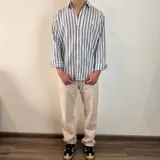 Camisa de manga larga con diseño de rayas verticales en tonos azul y blanco, cuello clásico y cierre frontal con botones.