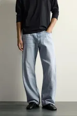 Jeans de denim de algodón en color azul con efecto desgastado, tiro medio y corte recto de ajuste holgado (loose fit). Cuenta con diseño clásico de cinco bolsillos y cierre frontal con cremallera y botón.