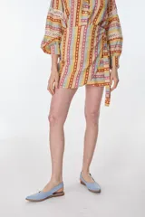 Minifalda estampada con motivos geométricos en tonos amarillo, naranja, celeste y rosa. Tiene corte evasé y lazo para ajustar en la cintura.