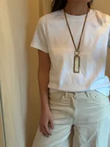 Collar largo con cordón de cuero marrón, aro de acero dorado y dije rectangular con marco plateado y relleno de guampa. Se cierra con cadena y gancho para regular el largo.