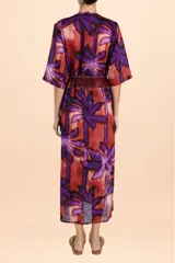 Cover up largo tipo túnica con escote en V, mangas tres cuartos y lazo ajustable en la cintura. Presenta un estampado vibrante de hojas en tonos púrpuras y cobrizos con detalles geométricos en los bordes frontales.