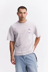 Remera de manga corta color lila, con escote redondo y fit regular. Presenta un estampado frontal de una manzana mordida con un gusano.